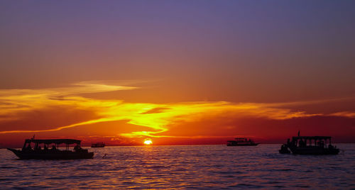 Silhouette boats sailing in sea against romantic sky at sunset