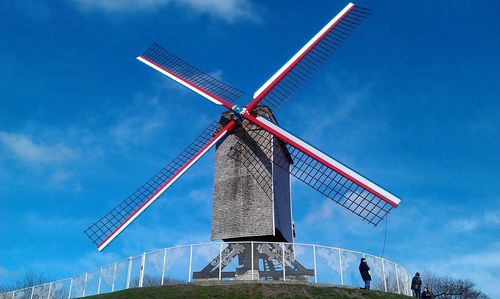 Low angle view of traditional windmill against blue sky