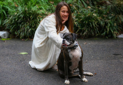 Portrait of smiling girl with dog crouching on road