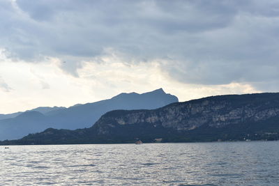 Scenic view of sea by mountains against sky