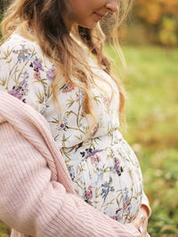 Midsection of pregnant woman standing on field