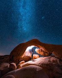 People standing on rock against sky at night