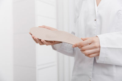 Midsection of businesswoman holding shoe sole