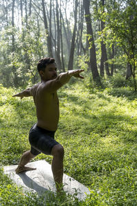 Millennial guy meditating with trainer online via tablet ipad connection, in the forest, broadcastin