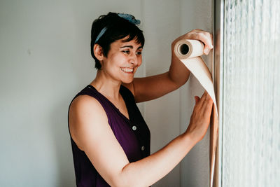 Portrait of smiling woman standing against wall