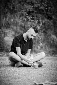 Young man looking away while sitting on land