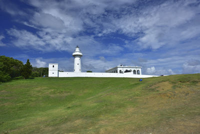 Lighthouse on grass against sky
