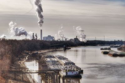 Smoke emitting from factory against sky