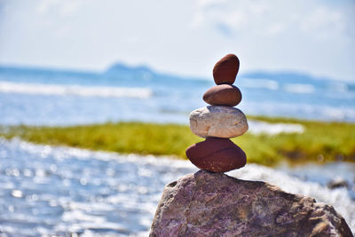 Stack of rocks by sea against sky