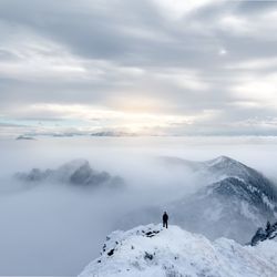 Person standing on snowcapped mountain against sky