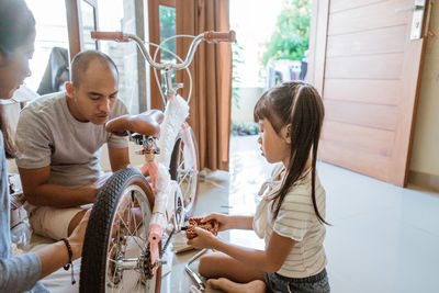 Family members repairing bicycle at home