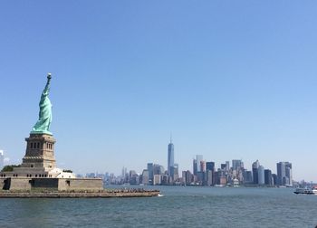Statue of liberty with buildings in background against clear sky