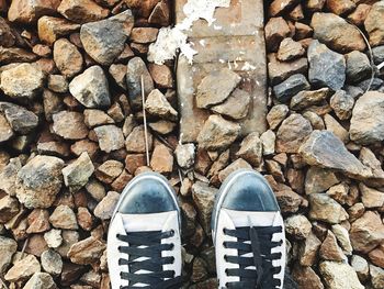 Low section of man wearing shoes standing on stones