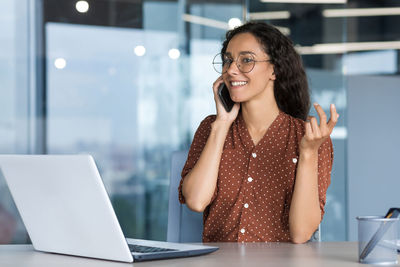 Businesswoman using laptop while sitting on table