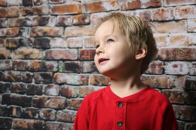 Portrait of smiling young boy against brick wall