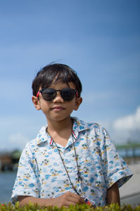 Portrait of boy wearing sunglasses while standing against sky