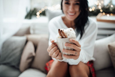 Midsection of woman holding hot chocolate while sitting at home
