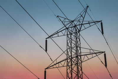 Low angle view of silhouette electricity pylon against sky