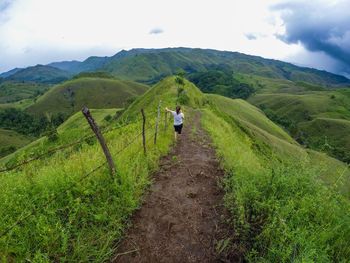 Rear view of man walking on mountain against sky