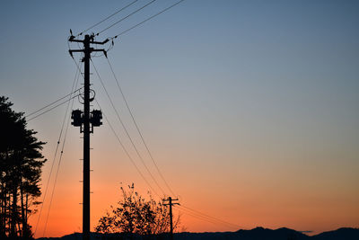 Low angle view of silhouette electricity pylon against sky during sunset