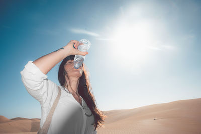 Midsection of woman drinking water in desert