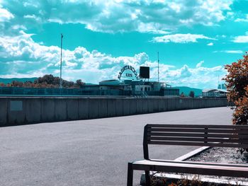 Empty bench by railing against sky