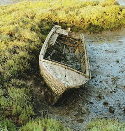 Abandoned boat moored on grass