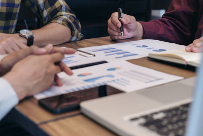 Close-up of colleagues discussing over graph at desk