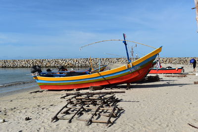 Boats moored on beach against sky