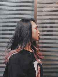 Close-up of woman looking away while standing against wall