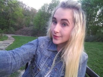 Portrait of smiling young woman against trees