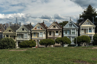 View of lawn and houses against cloudy sky