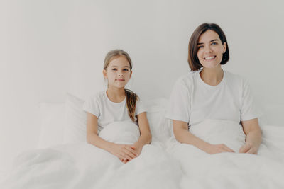 High angle view of mother and daughter sitting on bed