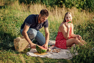 Happy loving couple kissing and having date outdoors. young couple on summer picnic with watermelon