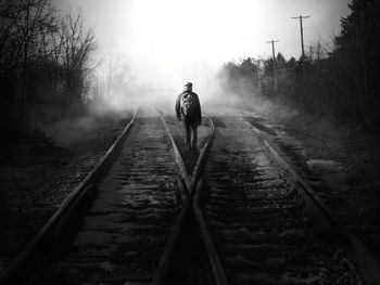 Rear view of silhouette man on railroad track