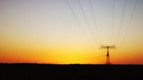 Silhouette electricity pylon on field against sky during sunset