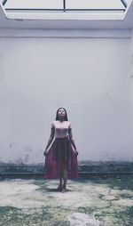 Young woman standing against wall