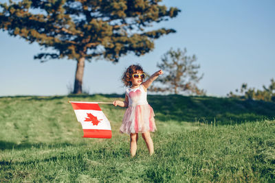 Full length of girl holding canadian flag on field