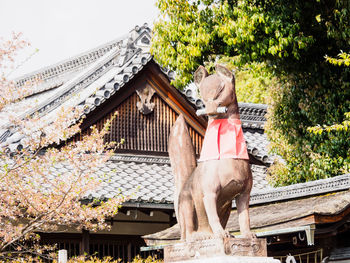 Low angle view of statue by building against sky