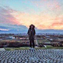 Silhouette of woman standing against cityscape at sunset