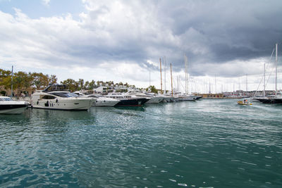 Sailboats moored at harbor against sky