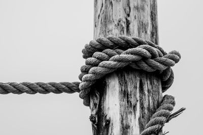 Close-up of rope tied to wooden post against sky