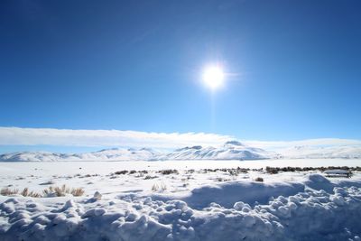 Scenic view of snow covered mountains against blue sky