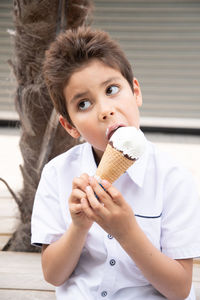 Cute child boy with a dirty face eats ice cream, the child enjoys dessert