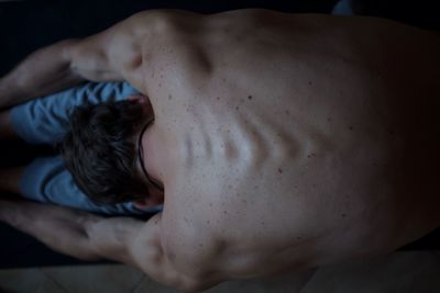 Rear view of shirtless man lying down