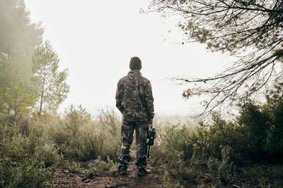 Rear view of man standing against clear sky