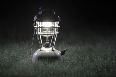 Close-up of illuminated lamp on field at night