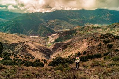 Rear view of woman standing on mountain against sky