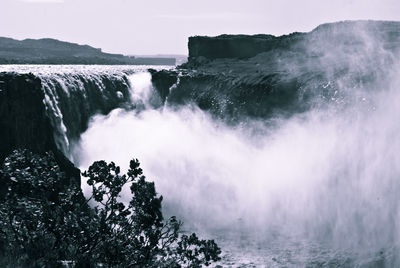 Scenic view of waterfall against sky