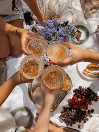 High angle view of four peoples hands  toasting drinks during  brunch picnic